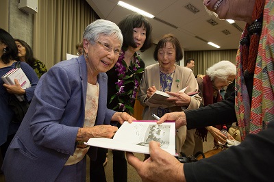 Rose Honda (left), a member of the Windsors club and adviser to the Atomettes, signs copies of City Girls with author Valerie Matsumoto (center) and Atomettes member Sadie Hifumi (right). Credit: Reed Hutchinson/UCLA.